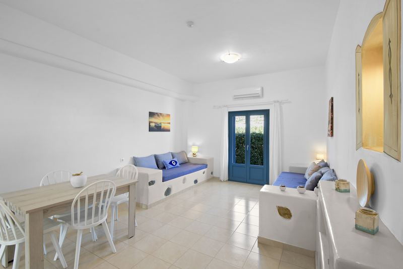Rose apartment, Flora Apartments Paros – living room with built-in sofas and dining area